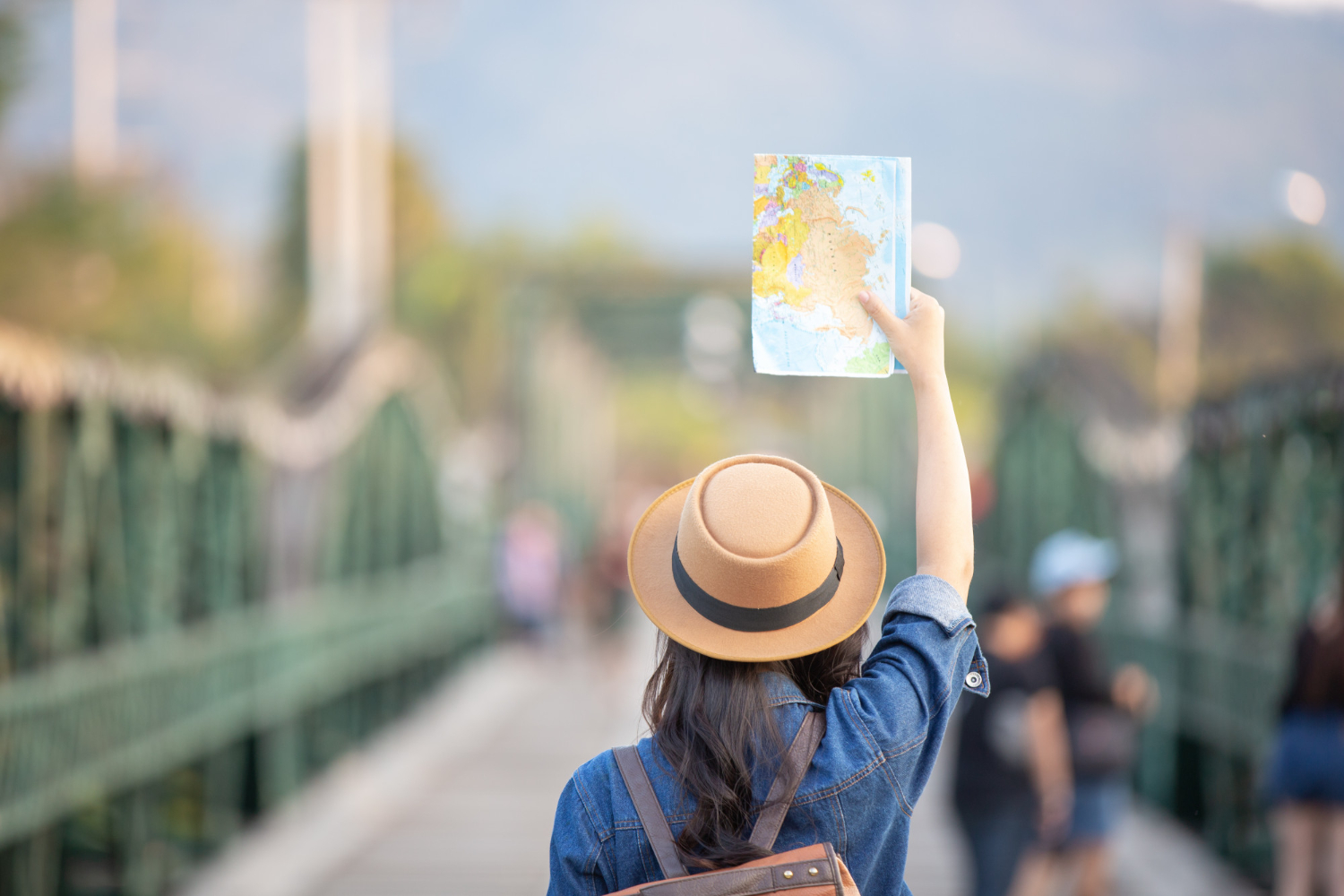 A woman traveler raising a printed world map